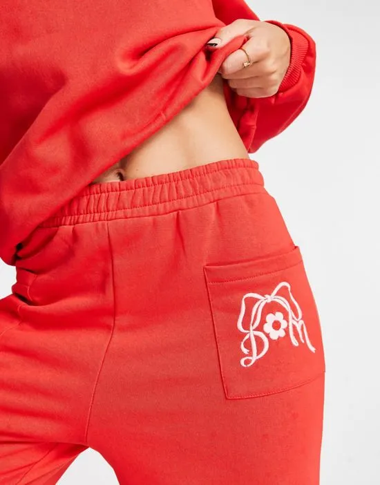 https://images.styletyx.com/images/cotton-bow-embroidered-sweatpants-in-red-part-of-a-set-damson-madder-3067463_2.webp