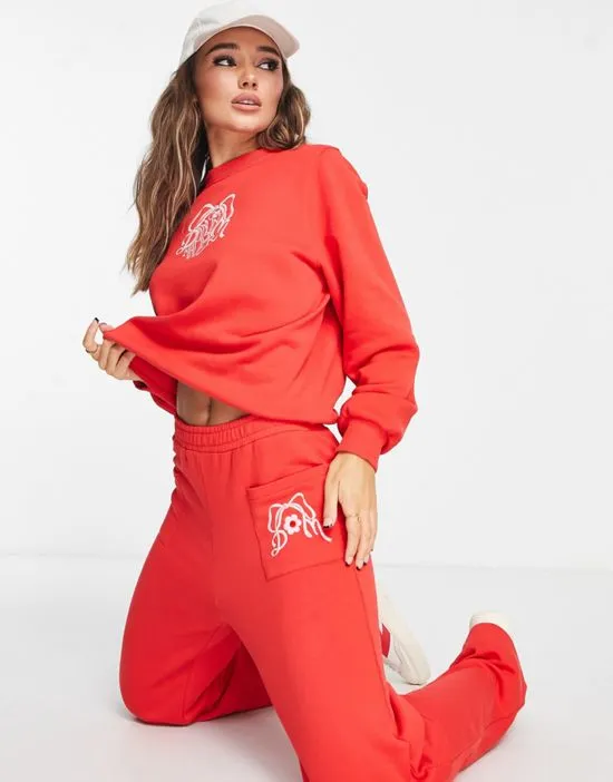https://images.styletyx.com/images/cotton-bow-embroidered-sweatpants-in-red-part-of-a-set-damson-madder-3067463_4.webp