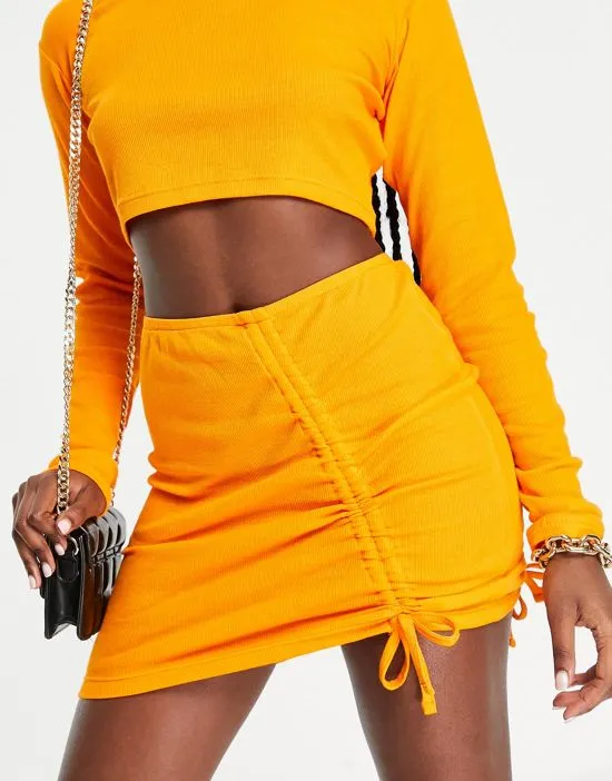 https://images.styletyx.com/images/ribbed-ruched-detail-mini-skirt-in-orange-part-of-a-set-the-couture-club-12998635_1.webp