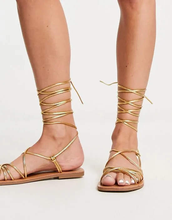 https://images.styletyx.com/images/strappy-tie-leg-flat-sandals-in-gold-london-rebel-wide-fit-13315870_4.webp