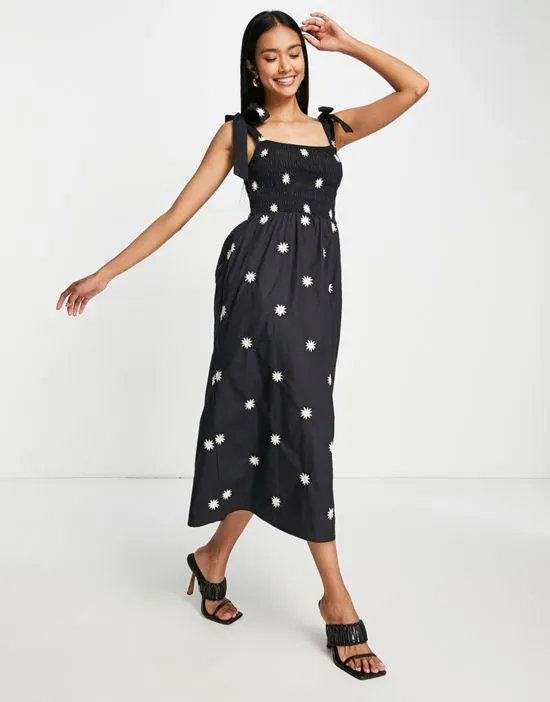 https://images.styletyx.com/images/tie-shoulder-daisy-embroidered-maxi-dress-in-black-never-fully-dressed-2962338_1.webp