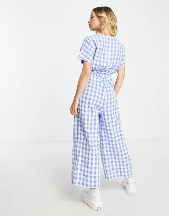 https://images.styletyx.com/images/tie-waist-seersucker-jumpsuit-in-blue-gingham-monki-2788748_4.webp